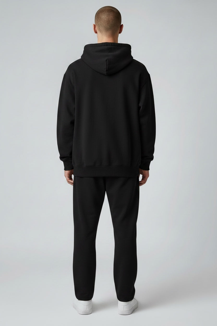 Back view of a man wearing a Pavel & Co black oversized heavyweight cotton-blend hoodie with ribbed hem and cuffs.