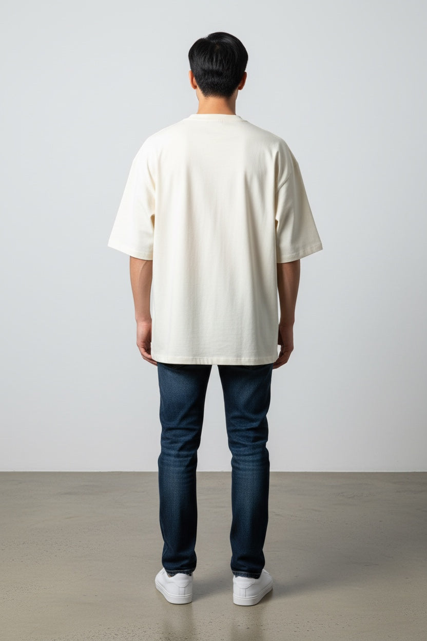 Back view of a man wearing a Pavel & Co Metropolis boxy fit cream heavyweight cotton t-shirt with dropped shoulders.